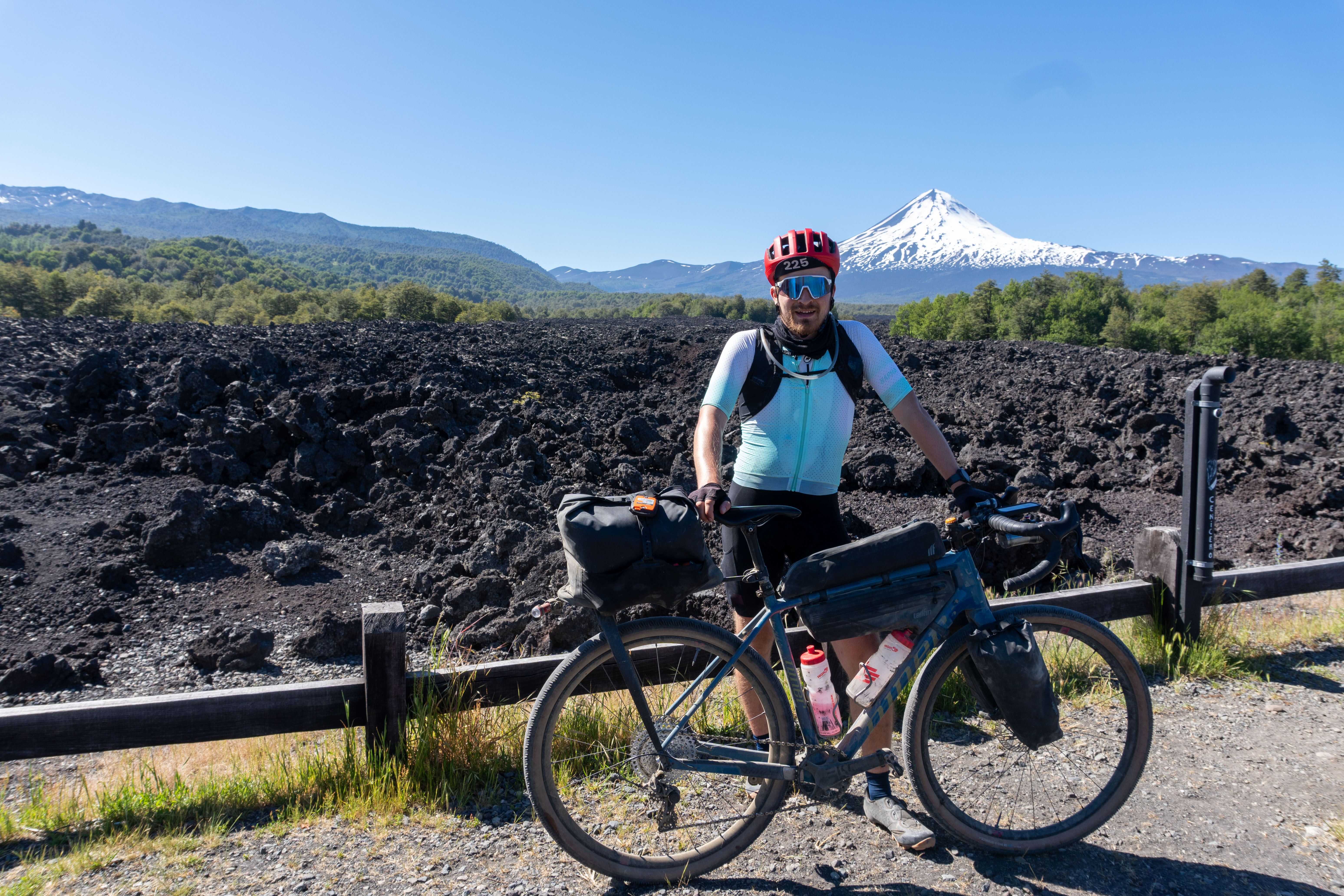 Oscar Huckle standing with a gravel bike in front of a volcano in Chile